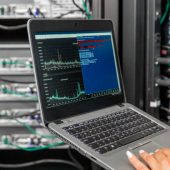 Female IT Engineer Using Laptopf for Analysis of Network Servers in Server Room.